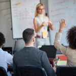 A woman gives a workshop amid a group of professionals.